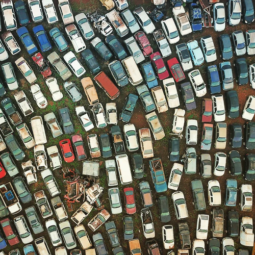 An aerial photograph of a junkyard with dozens of scrap cars.