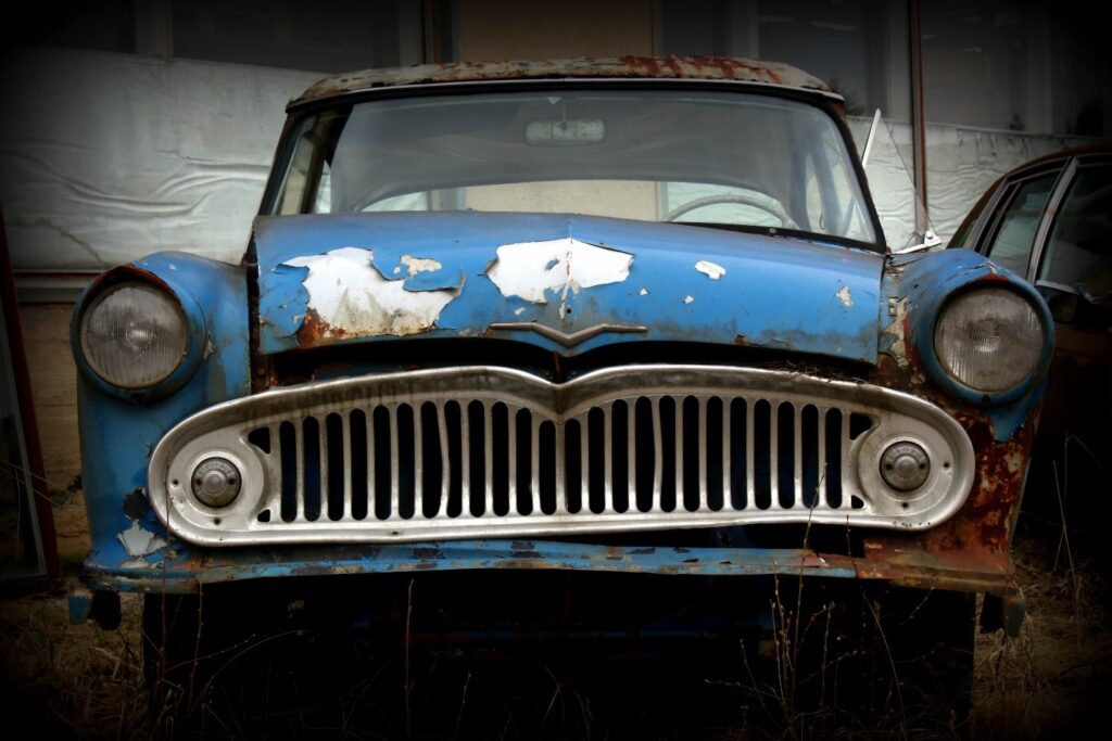 A blue junk car in a junkyard