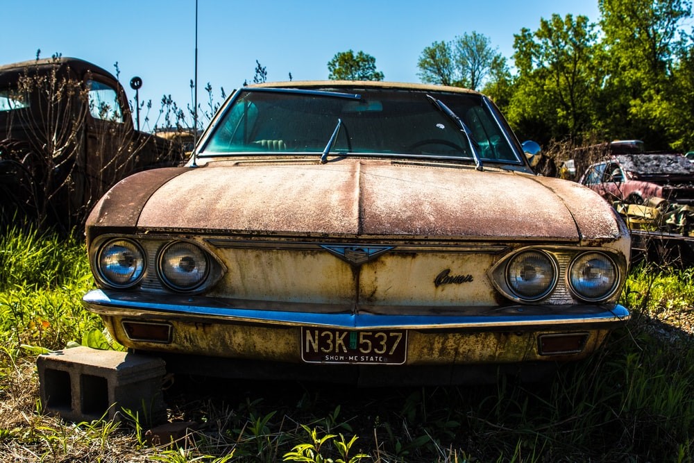rusted old junk car grass brick
