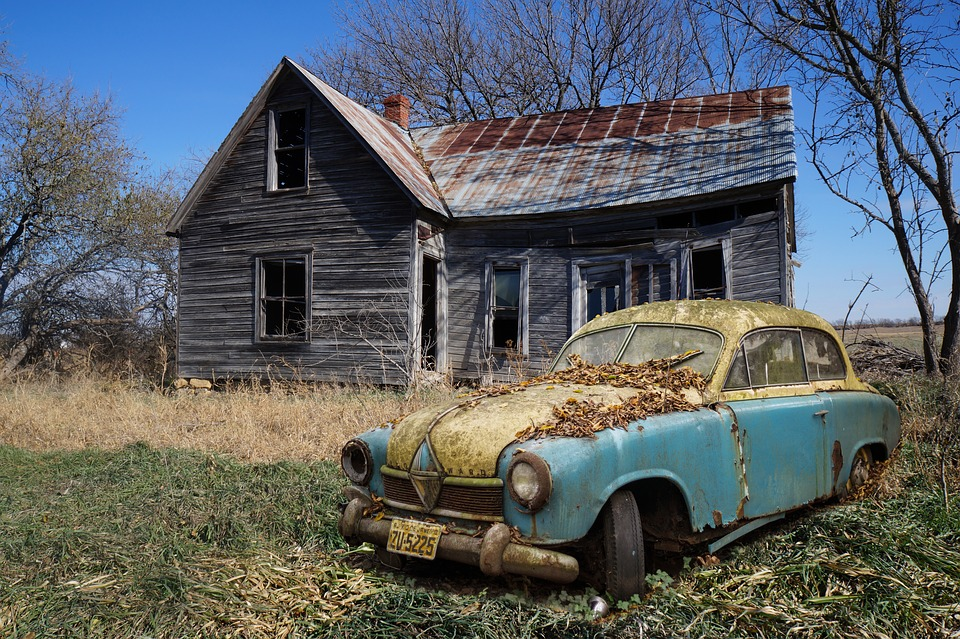 A picture of an old car in front of a house