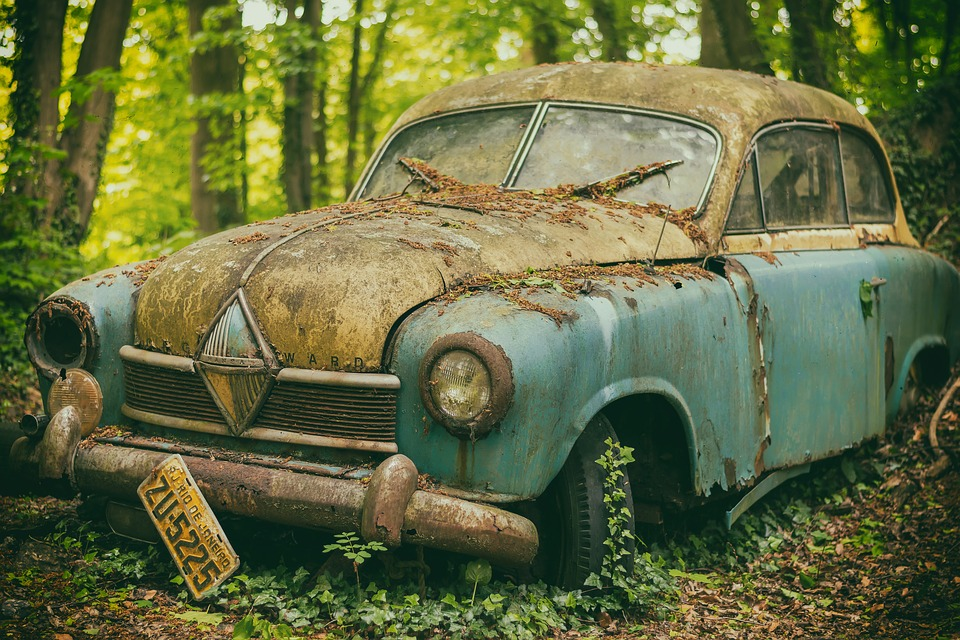An old rusty car abandoned in a forest