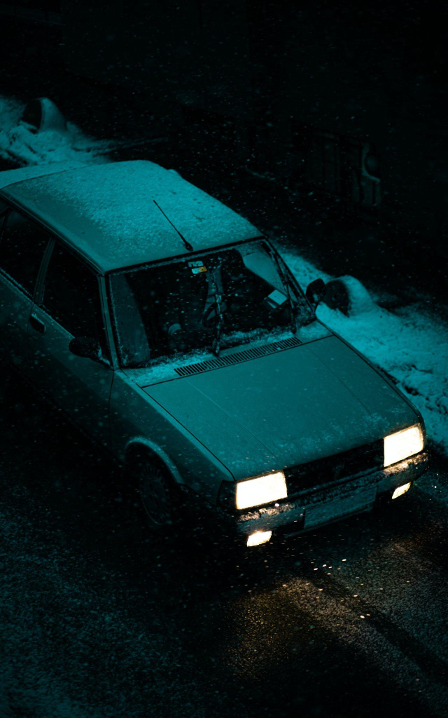 Someone driving an old car at night in the rain