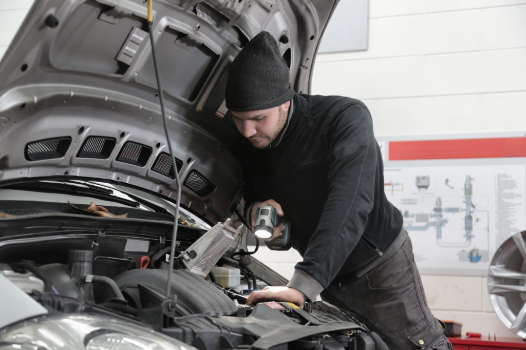 A man in black jacket inspecting car engine