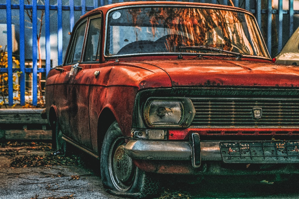 a beat-up-looking burnt orange colored sedan