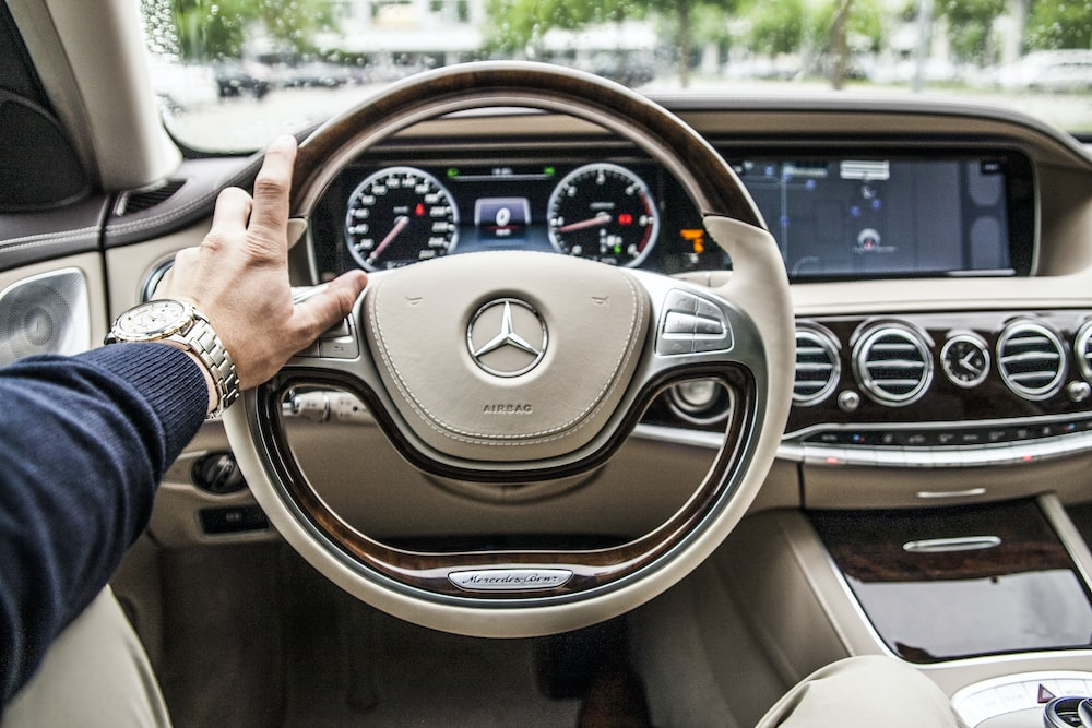 A person running their hand around the steering wheel of a car.