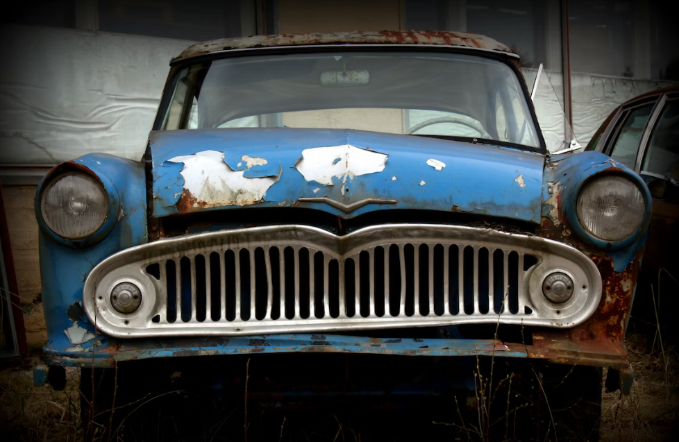 Blue junk car in a yard.