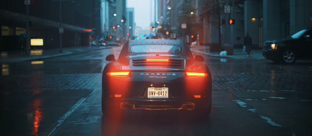 A photo showing the rear of a black car on a rainy day.