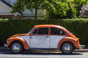 A photo showing an orange Volkswagen Beetle.