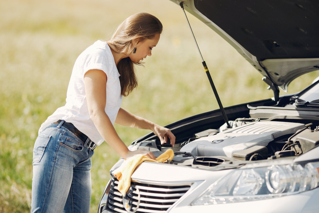 A photo showing a woman examining a blown car engine.