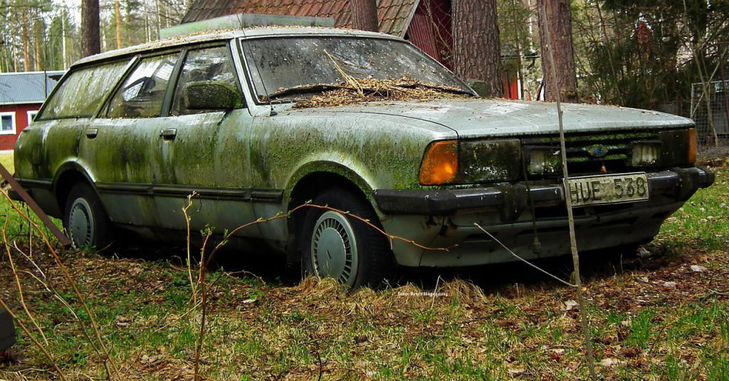 An old, rusty truck parked in a junkyard.