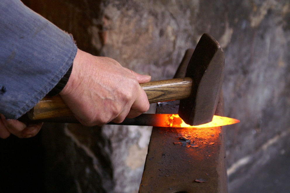 Person forging scrap metal with a hammer 