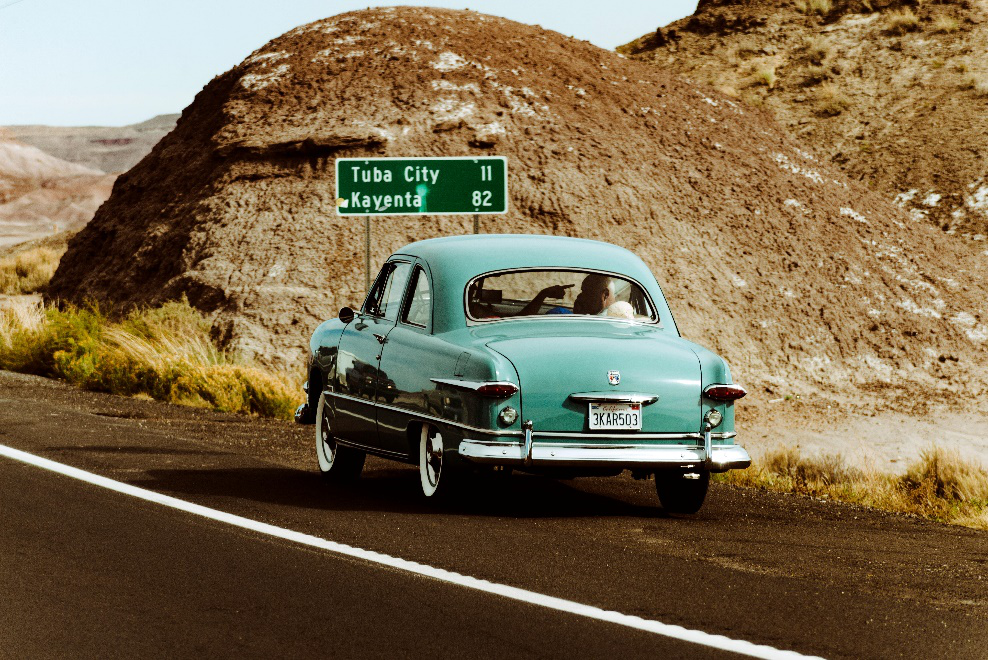 A teal colored beetle on the road