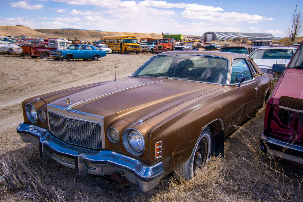 A brown vintage car standing in a junkyard