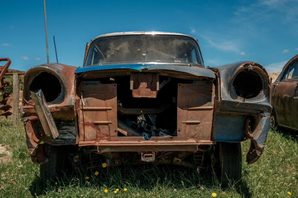 Front view of a junk care standing in grass with no headlights.