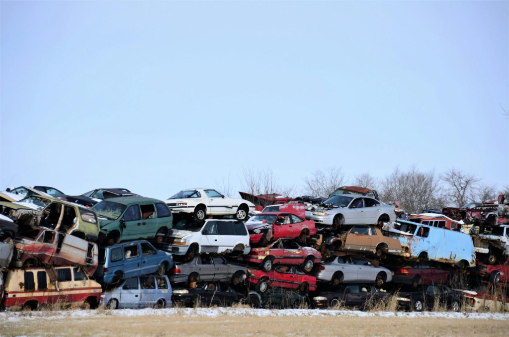 Three to four tiered pile of junk cars in different colors.