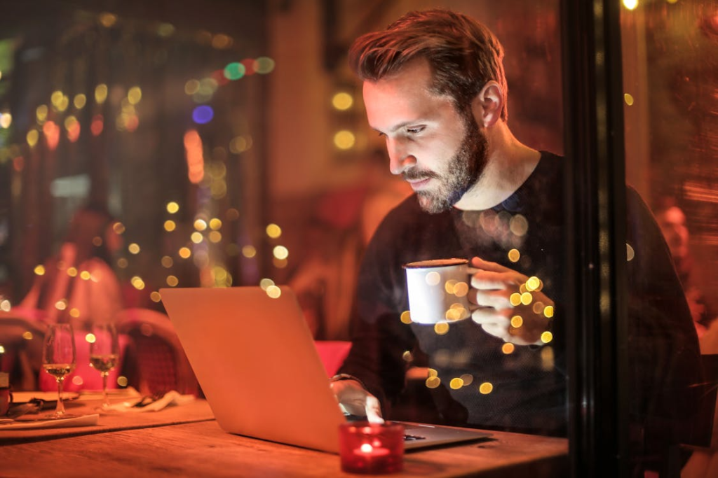 Man holding a mug in front of a laptop