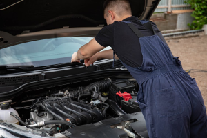 A mechanic in a black t-shirt fixing a car engine