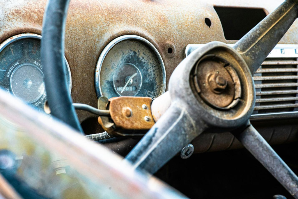 Close-up of an old car’s rusted steering wheel.